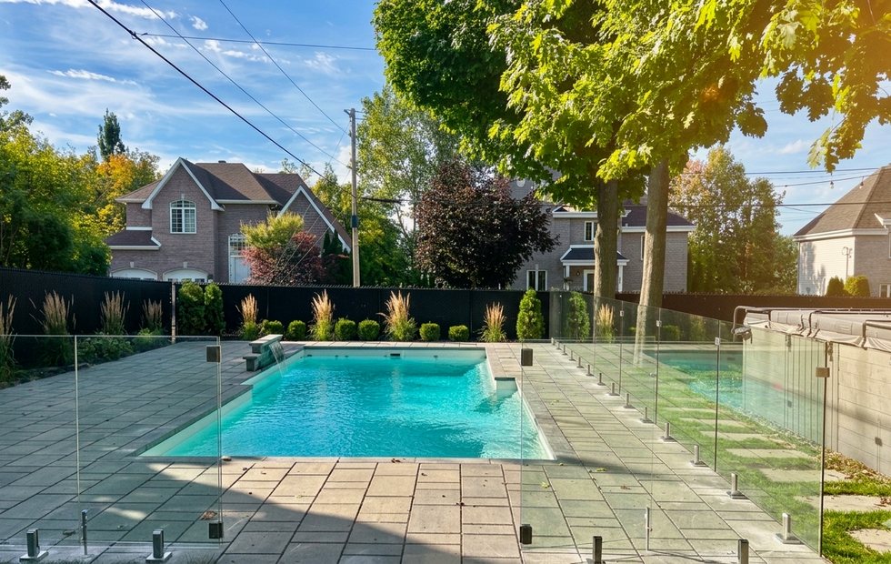 Grande piscine avec clôture en verre et aménagement résidentiel